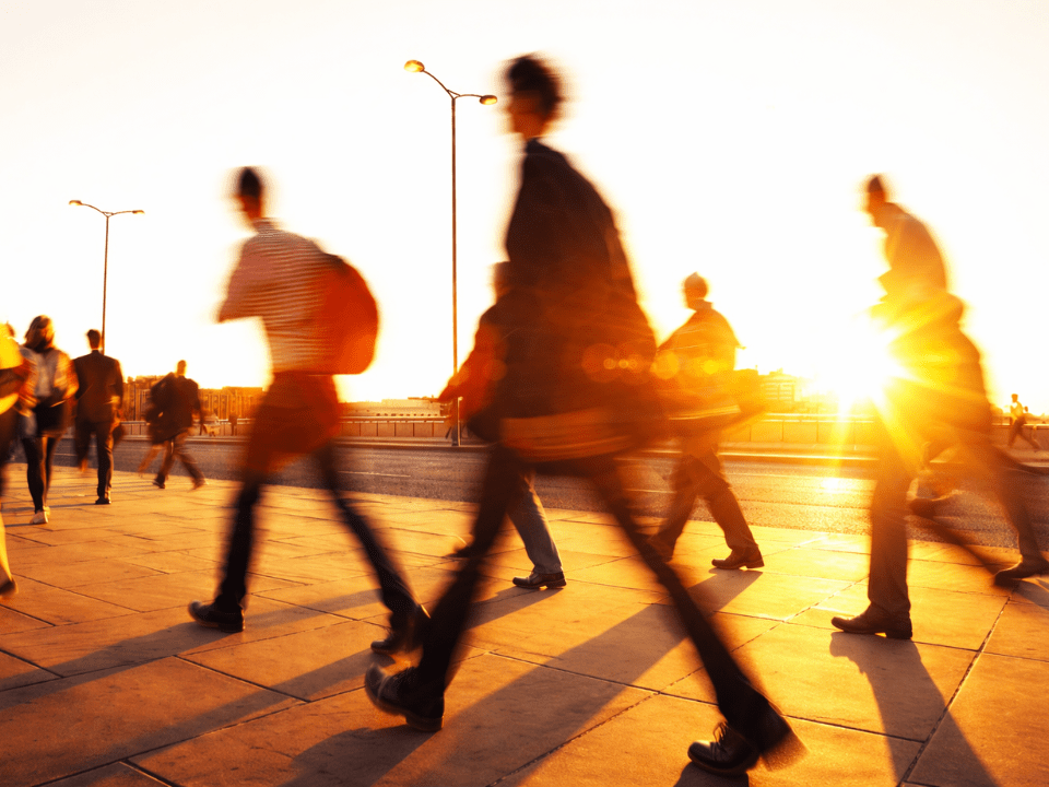 Pessoas caminham sob sol intenso em ambiente urbano durante onda de calor extremo, com forte luminosidade e altas temperaturas.