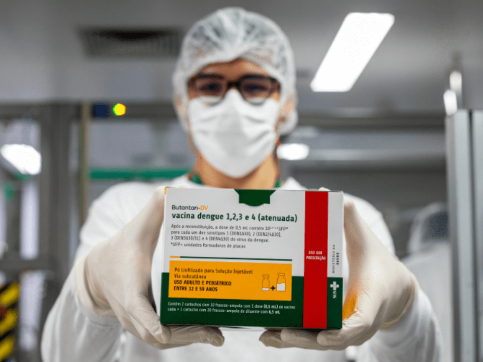 Vacina da dengue do Butantan apresentada por profissional de saúde em ambiente de laboratório, imunizante nacional de dose única destinado à prevenção da dengue no SUS.