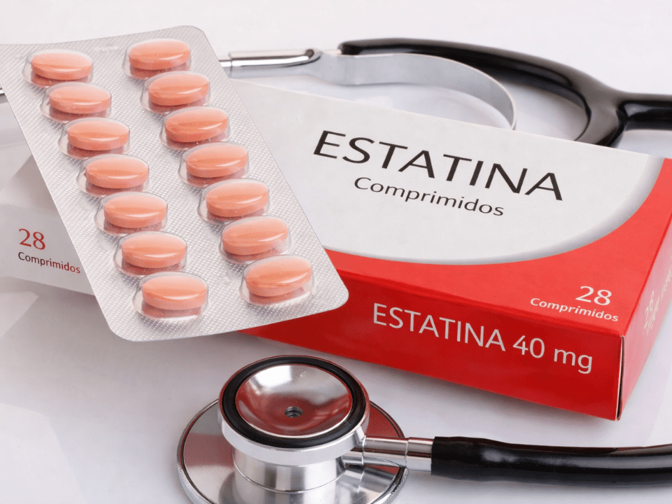 Embalagem de estatina com comprimidos em blister e estetoscópio ao fundo, ilustrando estudo sobre dor muscular associada ao uso de estatinas e implicações clínicas.