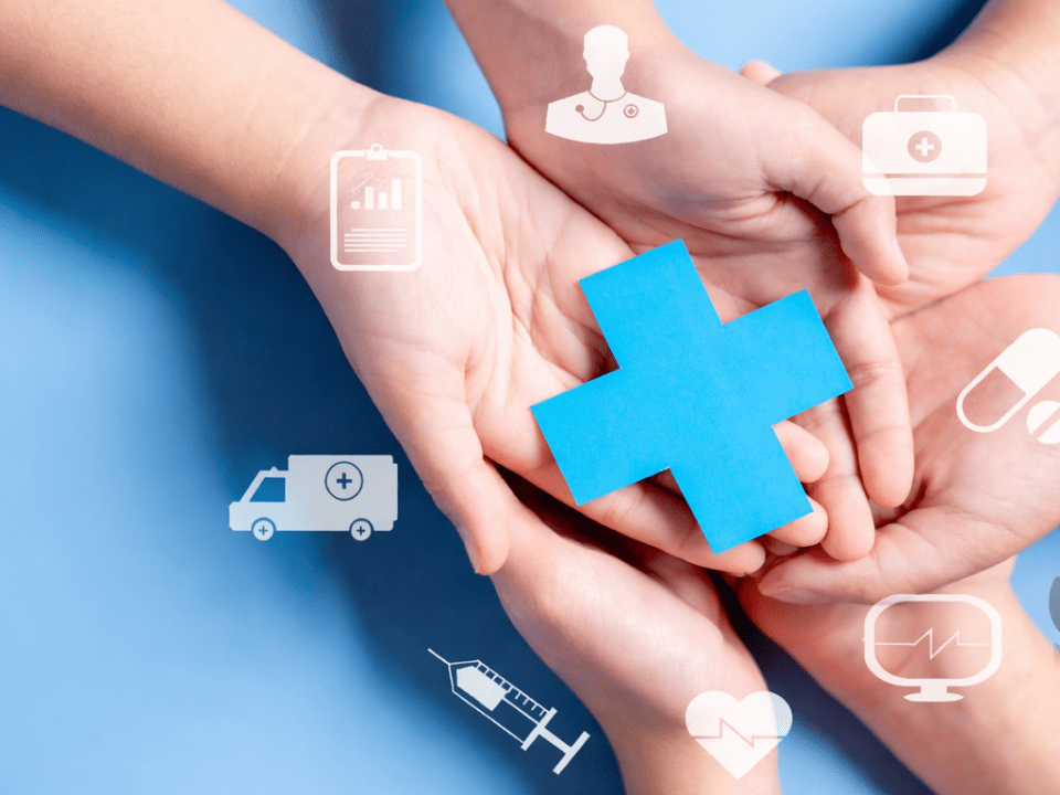 Mãos segurando símbolo de cruz azul representando assistência em saúde, rede assistencial e direitos do paciente.