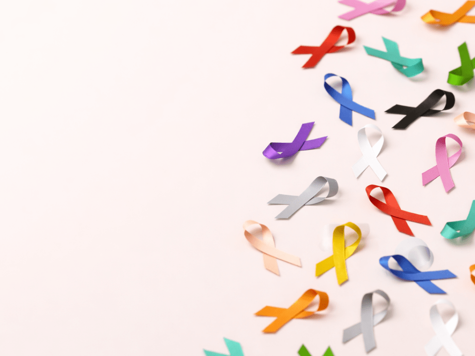 Ribbons coloridos de conscientização sobre diferentes tipos de câncer dispostos sobre fundo claro, simbolizando prevenção, diagnóstico e cuidado oncológico.