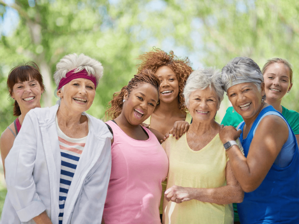 Grupo de mulheres de diferentes idades sorrindo ao ar livre representando saúde da mulher e bem-estar feminino.