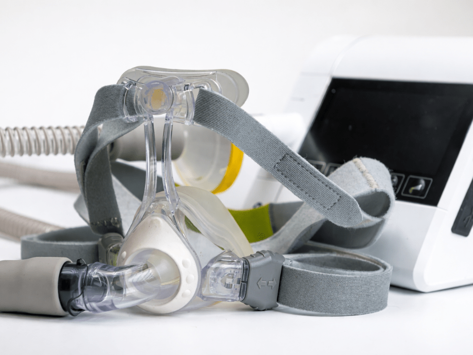 Máscara respiratória com estrutura transparente e canais internos visíveis para coleta de condensado do ar exalado, conectada a sistema clínico, em ambiente laboratorial controlado, representando monitoramento contínuo de biomarcadores respiratórios sem bateria.