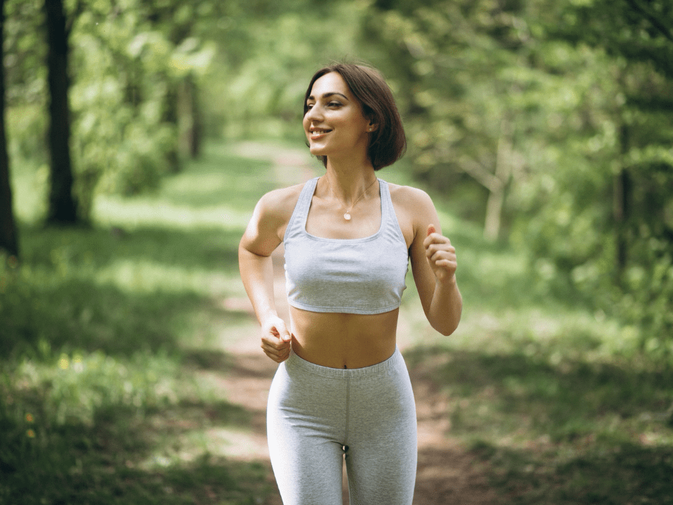 Mulher praticando corrida ao ar livre em área verde, representando hábitos saudáveis e cuidado com a saúde vascular feminina.