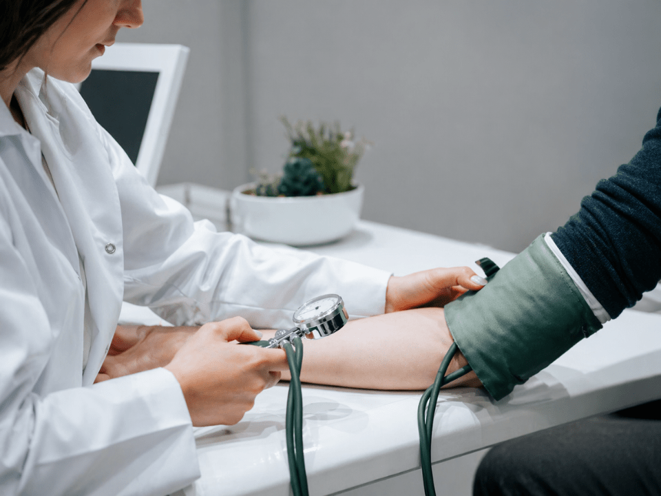 Profissional de saúde realizando aferição de pressão arterial com manguito, em contexto clínico relacionado ao uso do zilebesiran para hipertensão.