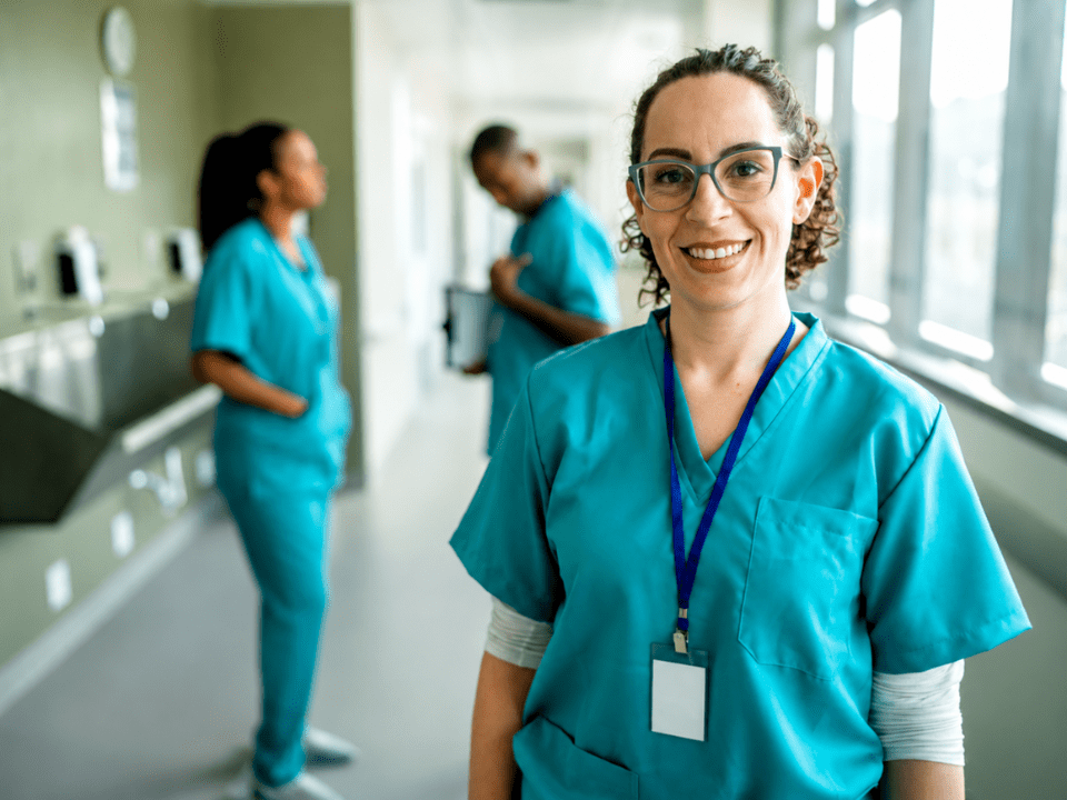 Profissional de enfermagem em corredor hospitalar durante atendimento clínico no Dia Internacional da Enfermagem, representando o papel da enfermagem na segurança do paciente e na medicina diagnóstica.
