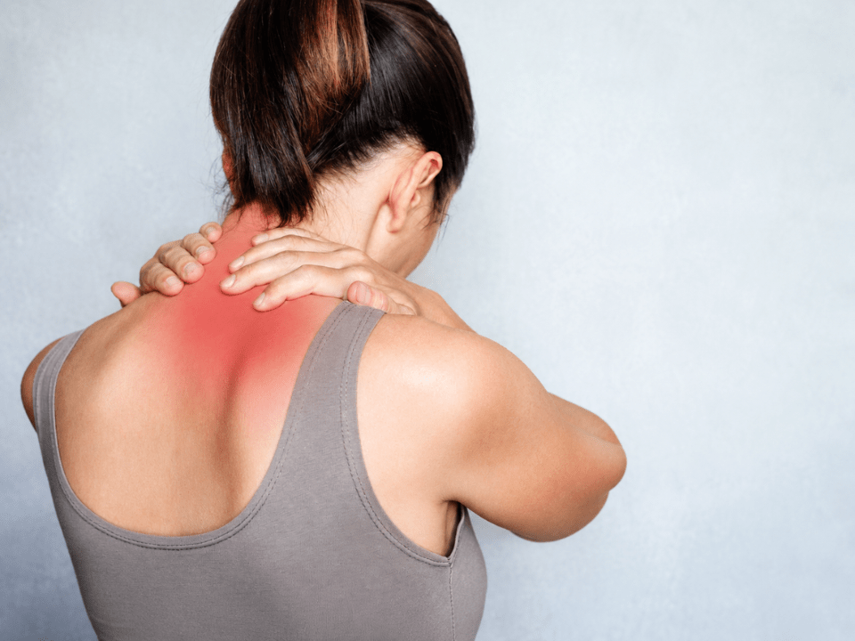Mulher com dor muscular na região cervical e nos ombros, ilustrando os impactos da fibromialgia e fadiga crônica em imagem editorial relacionada à medicina diagnóstica e saúde.