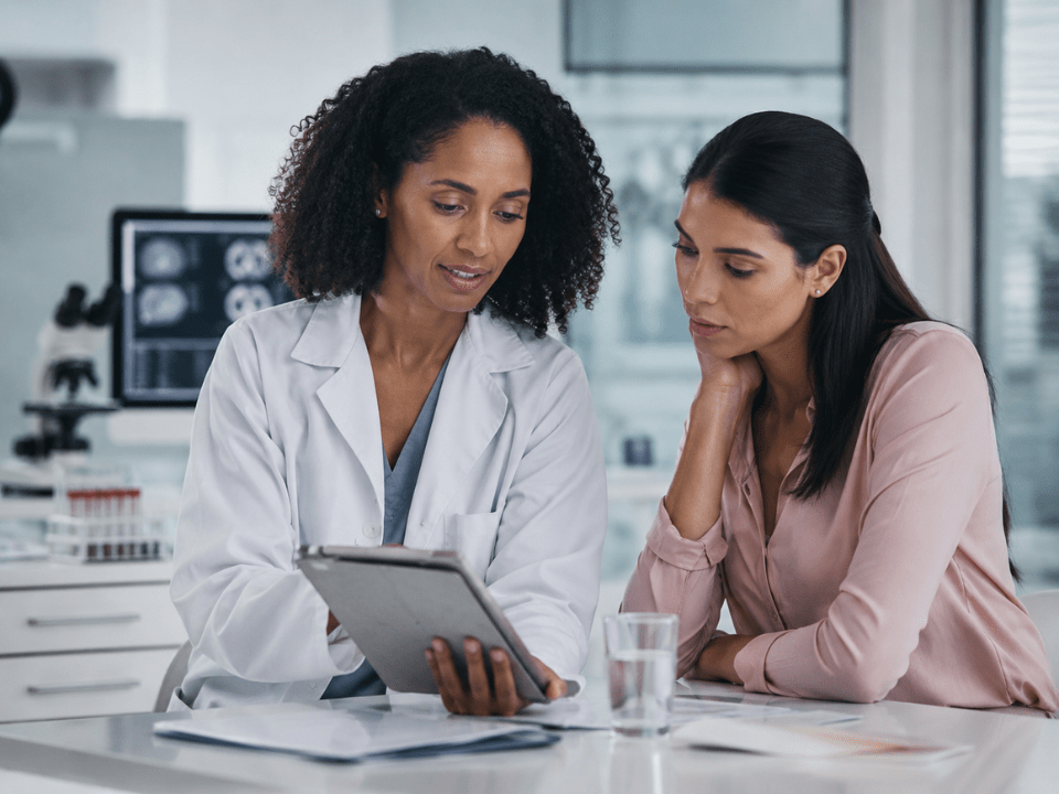 Profissional de saúde realiza atendimento clínico feminino em ambiente hospitalar, representando os desafios da saúde da mulher relacionados ao diagnóstico, prevenção e cuidado integral.