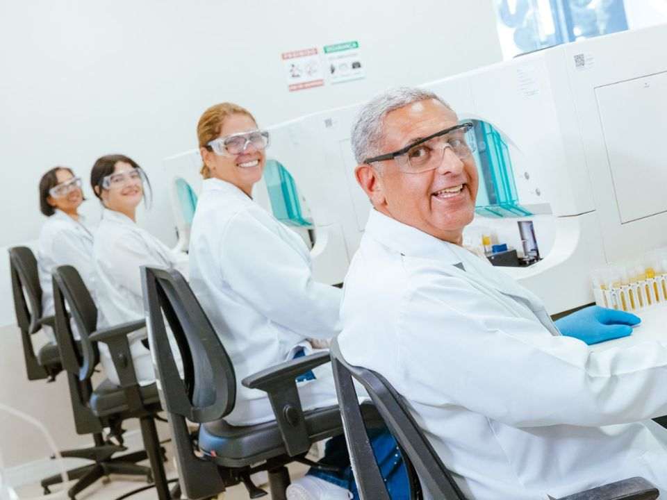 Especialistas da AFIP trabalham em ambiente laboratorial de alta tecnologia, monitorando análises e processos diagnósticos. A fotografia representa a cultura organizacional na medicina diagnóstica, evidenciando integração entre profissionais, capacitação contínua, liderança, gestão de pessoas e compromisso com a qualidade dos serviços de saúde e medicina laboratorial.